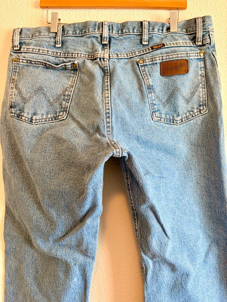 Puede incluir: Vaqueros de mezclilla azul claro con el logo de Wrangler en el bolsillo trasero. Los vaqueros tienen un dise&ntilde;o cl&aacute;sico de cinco bolsillos con corte recto. Los bolsillos traseros presentan costuras en forma de W.