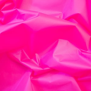 May include: A close-up of a bright pink fabric with a smooth, silky texture. The fabric is wrinkled and folded, creating a soft, flowing look.