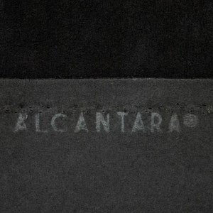 May include: Close-up of a black fabric with the word "ALCANTARA" embossed in white.