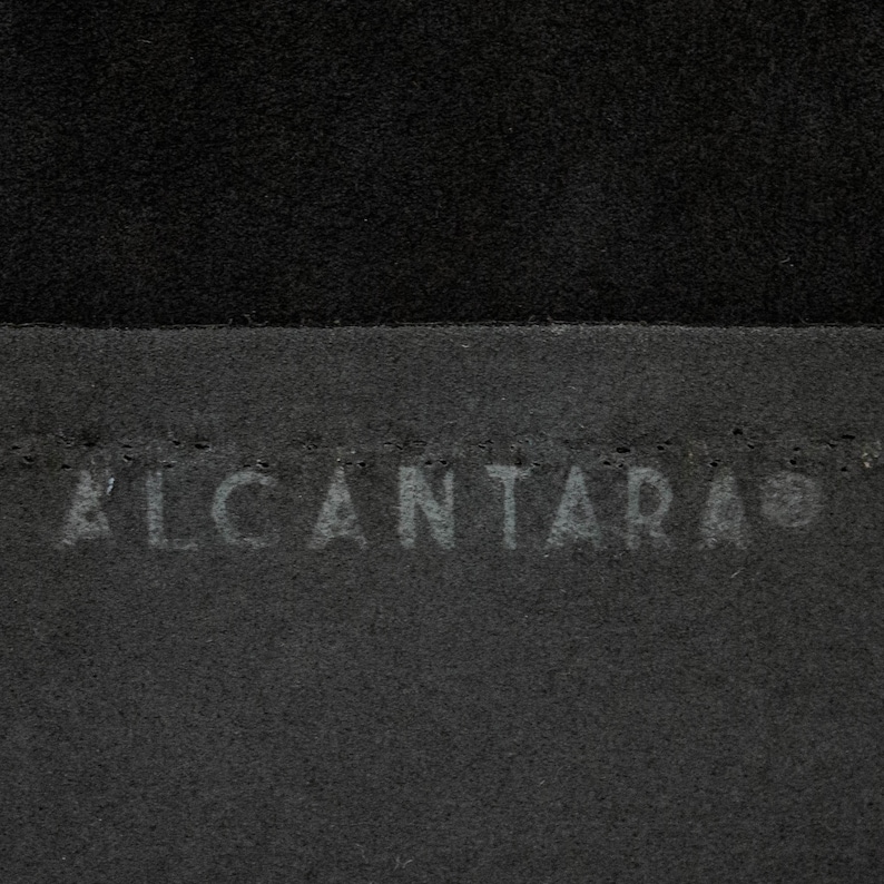 May include: Close-up of a black fabric with the word "ALCANTARA" embossed in white.