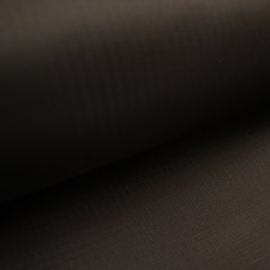 May include: Close-up of a dark brown fabric with a subtle texture. The fabric is rolled up, creating a soft, curved shape.