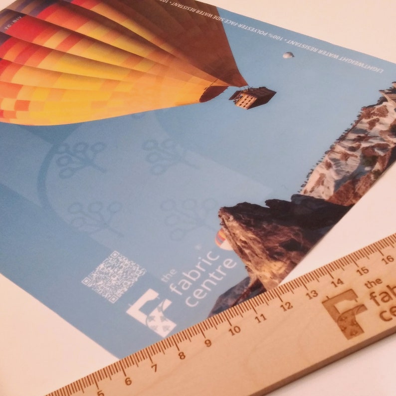 May include: A colorful hot air balloon flies over a rocky landscape. The image is a promotional flyer for "the fabric centre" with a QR code and a stylized "F" logo.