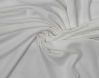 Op de afbeelding: Witte stof met een gladde textuur, gedrapeerd en gevouwen om een ​​zachte, vloeiende look te creëren.