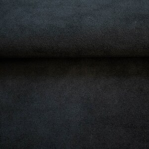 May include: Close-up of a dark gray fabric with a soft, fuzzy texture. The fabric is folded in half, showing the inside and outside of the material.