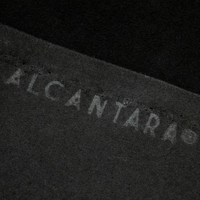May include: Close-up of black fabric with the word "ALCANTARA" embossed in white.