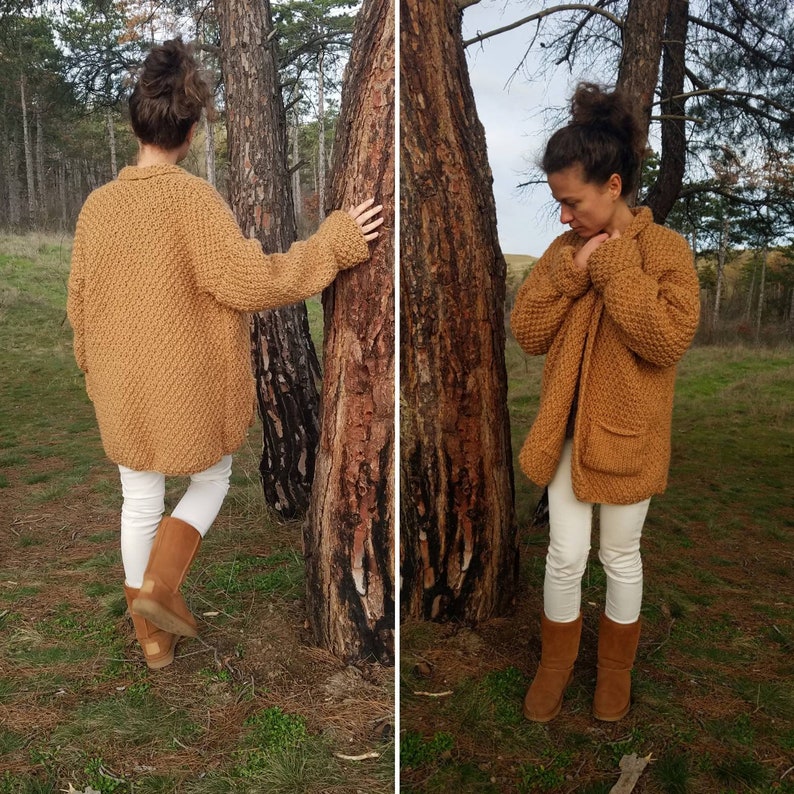 May include: A mustard-colored, chunky knit cardigan with two front pockets. The open-front sweater has a textured pattern and long sleeves. The model is wearing white pants and brown boots. The cardigan is a warm, cozy outerwear option.