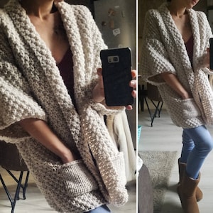 May include: A chunky knit, open-front cardigan in a neutral beige color. The cardigan features large pockets and a relaxed fit. The sleeves are three-quarter length. The textured knit creates a cozy, oversized look, perfect for layering.