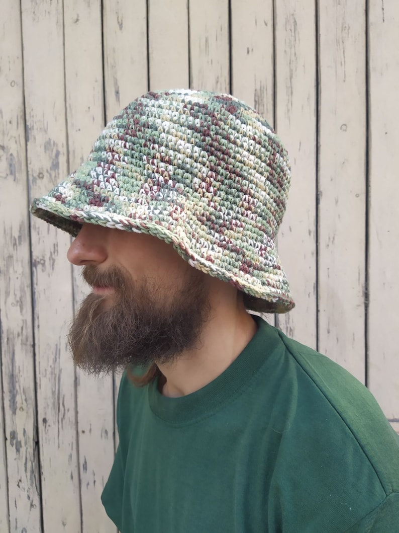 May include: A green, white, and brown crocheted bucket hat with a wide brim.