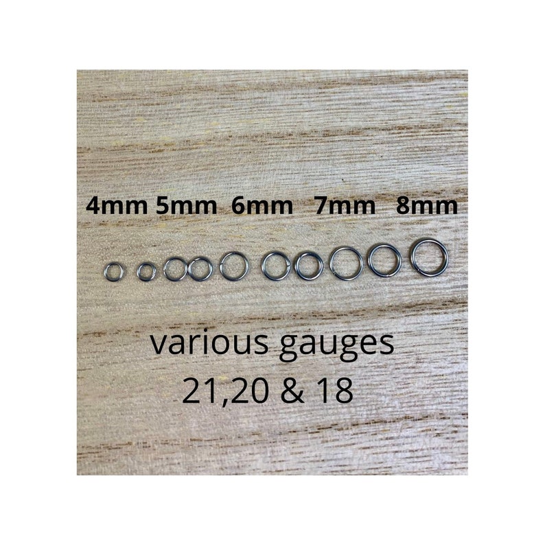 May include: A collection of silver-colored jump rings in various sizes, ranging from 4mm to 8mm, displayed on a wooden surface. The image includes text indicating the sizes and gauges 21, 20, and 18.