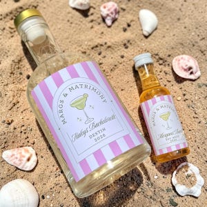 May include: A large clear glass bottle and a smaller clear glass bottle, both with gold and silver caps, featuring custom labels with pink and white vertical stripes, a margarita illustration, and the text Margs & Matrimony, Haleys Bachelorette Destin 2026 and Morgans Bachelorette Key West 2025.