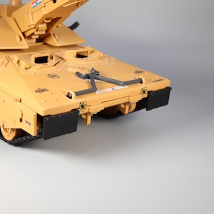 Puede incluir: Tanque de juguete de color beige con orugas y detalles negros. El tanque tiene una torreta elevada y el texto "ACTION FORCE" es visible. El tanque tiene paneles negros en la parte delantera.