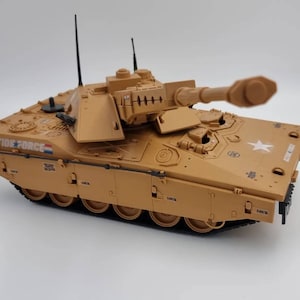 May include: A tan toy tank with a large cannon and a white star on the side. The tank has the words "ACTION FORCE" printed on the side.