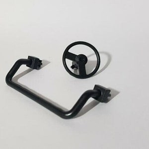 Op de afbeelding: Zwart plastic stuurwiel en een zwart plastic gebogen handvat met een connector aan elk uiteinde.