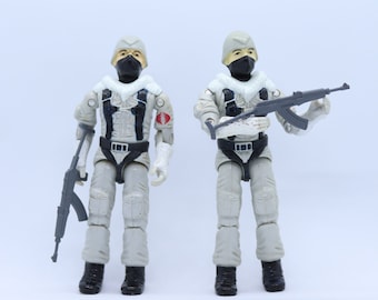 Peut inclure: Deux figurines d'action blanches avec des masques et des casques noirs, tenant des armes à feu. Les figurines portent des vêtements d'hiver blancs et ont un logo Cobra sur la poitrine.