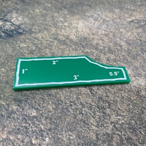 Peut inclure: Un gabarit en plastique vert avec des lignes blanches et des mesures en pouces. Le gabarit a la forme d'un rectangle avec un bord incurv&eacute;. Les mesures sont de 1", 2", 3" et 0,5".