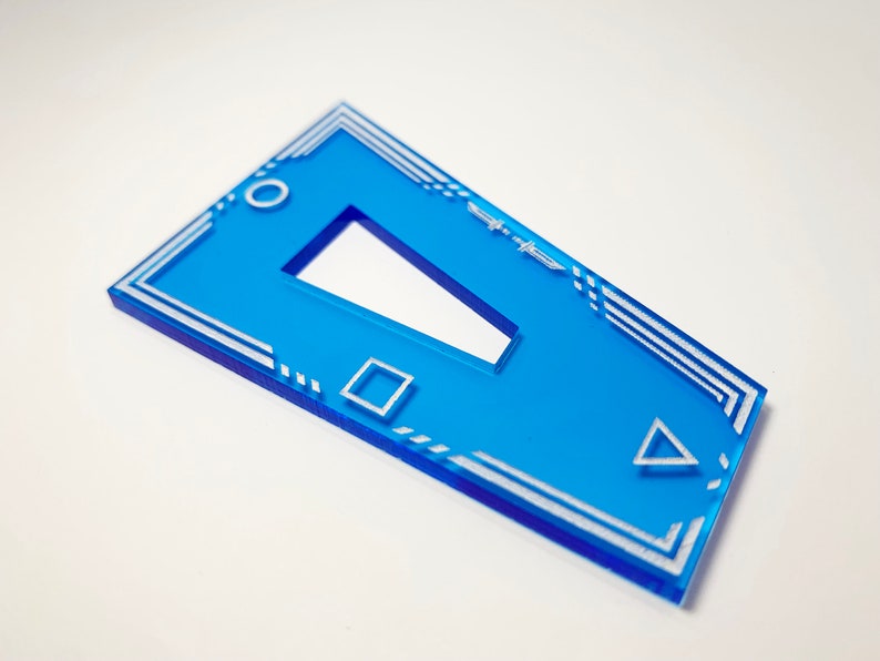 K&ouml;nnte beinhalten: Ein blauer Acryl-Schl&uuml;sselanh&auml;nger mit einem wei&szlig;en geometrischen Design. Das Design beinhaltet ein Quadrat, ein Dreieck und ein Rechteck. Der Schl&uuml;sselanh&auml;nger hat oben ein Loch zum Anbringen an einem Schl&uuml;sselring.