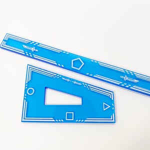 K&ouml;nnte beinhalten: Zwei blaue Acryl-Lineale mit wei&szlig;en geometrischen Mustern. Das gr&ouml;&szlig;ere Lineal hat eine f&uuml;nfeckige Form in der Mitte und das kleinere Lineal hat einen Kreis, ein Quadrat und ein Dreieck.