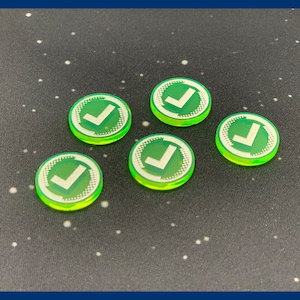 Puede incluir: Cinco fichas de juego redondas verdes y blancas. Cada ficha presenta un símbolo de verificación blanco dentro de un círculo verde. Los bordes de las fichas tienen un aspecto verde translúcido y brillante.