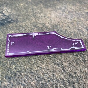 Peut inclure: Une r&egrave;gle en plastique violette avec des marques blanches. La r&egrave;gle mesure 7,6 cm de long et comporte des marques pour 2,5 cm, 5 cm, 1,3 cm et 7,6 cm.