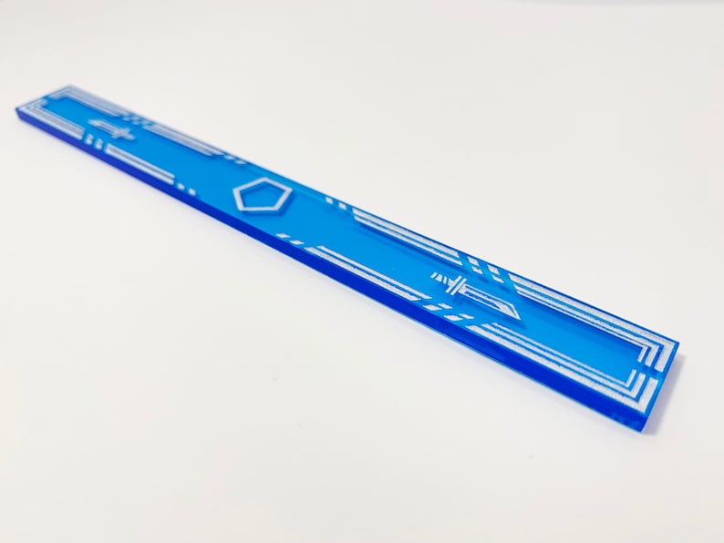 K&ouml;nnte beinhalten: Ein blauer Acryl-Lineal mit einem wei&szlig;en geometrischen Muster und einer Schwertdarstellung. Das Lineal ist etwa 30 cm lang.