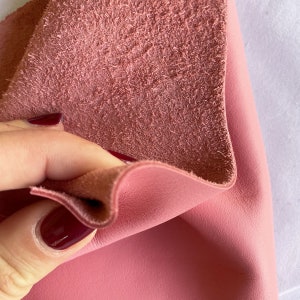 May include: Close-up of a pink leather fabric with a suede texture on the reverse side.
