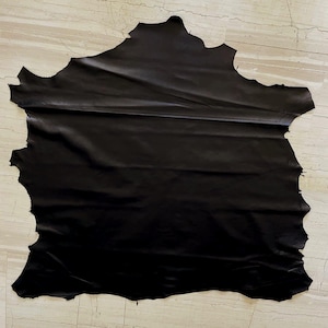 Könnte beinhalten: Ein rustikales Holzschild mit dem handgeschriebenen Wort "Welcome". Das Schild ist weiß gestrichen und hat einen Used-Look. Ein kleines Herz ist unten angebracht. Der Hintergrund ist eine verschwommene Holzoberfläche.