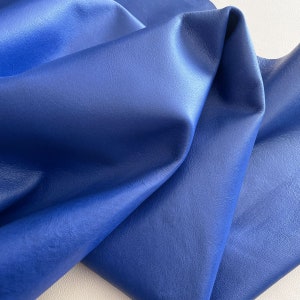 Puede incluir: Primer plano de un trozo de cuero azul doblado. El cuero tiene una superficie lisa y texturizada.