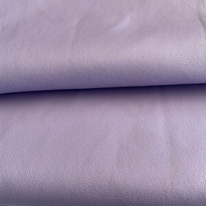 May include: A close-up of a soft, light purple fabric with a textured surface.