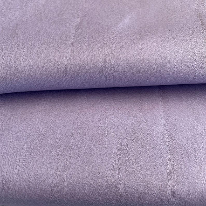 May include: A close-up of a soft, light purple fabric with a textured surface.