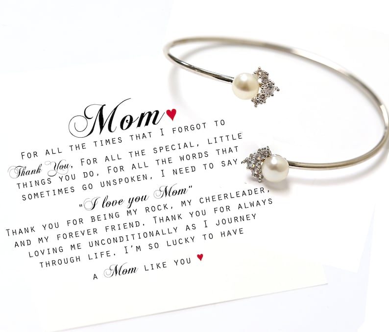 May include: A silver bangle bracelet with two pearl charms and a card with the text "Mom" and a message of appreciation for a mother. The card reads "For all the times that I forgot to thank you, for all the special, little things you do, for all the words that sometimes go unspoken, I need to say "I love you Mom." Thank you for being my rock, my cheerleader, and my forever friend. Thank you for always loving me unconditionally as I journey through life. I'm so lucky to have a Mom like you."