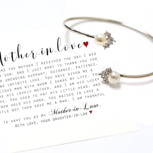 May include: A white card with a silver bracelet and two pearls. The card has a handwritten message that reads "Mother-in-love You are the mother I received the day I wed your son, and I just want to thank you for your unending support, guidance, patience, and infinite love. You have given me a gracious man with whom I share my life. You are his lovely mother, and I am his lucky wife. You used to pat his little head, and I now hold his hand. You raised in love a little boy then gave me a man. I am thankful to have you as my Mother-in-Law. With love, your daughter-in-law."