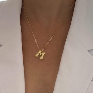 May include: A gold chain necklace with a chunky, stylized letter 'M' pendant.