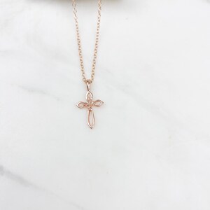 Puede incluir: Un delicado collar de cadena de oro rosa con un peque&ntilde;o colgante de cruz adornado.