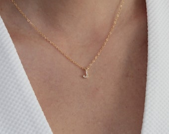 May include: A gold chain necklace with a small, diamond-encrusted letter J pendant.