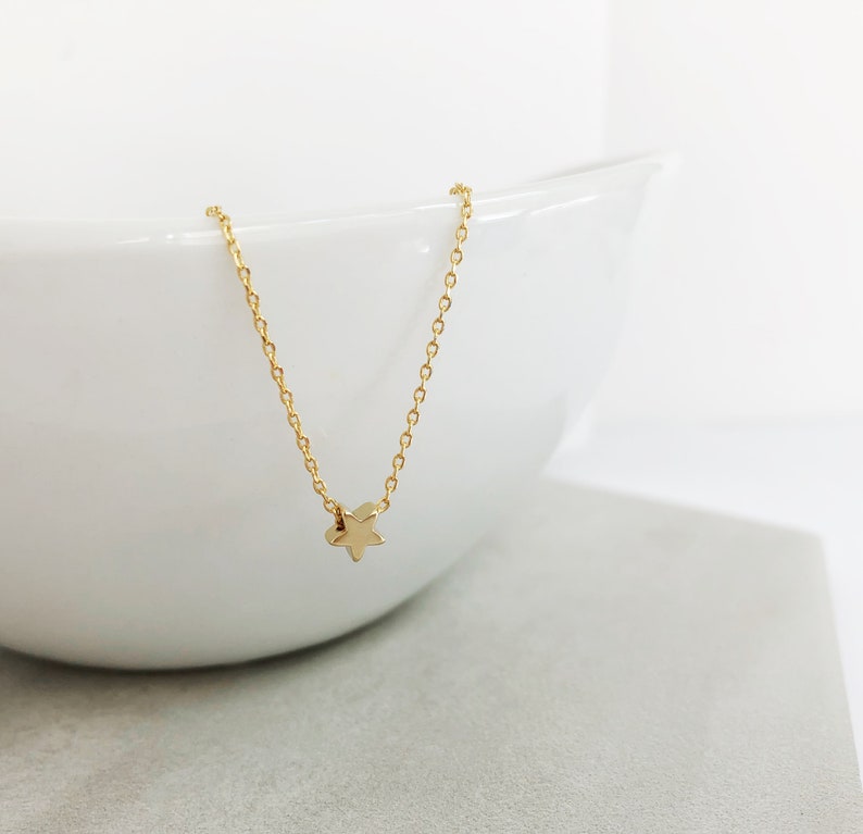 Peut inclure: Un collier d&eacute;licat en cha&icirc;ne dor&eacute;e avec un petit pendentif en forme d'&eacute;toile.
