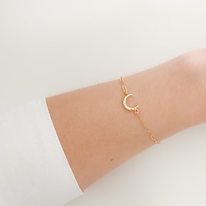 May include: A gold crescent moon charm bracelet with a delicate chain.