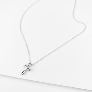 May include: A silver chain necklace with a small, simple silver cross pendant.