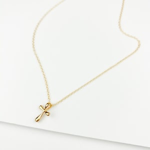 May include: A gold chain necklace with a small, delicate gold cross pendant.