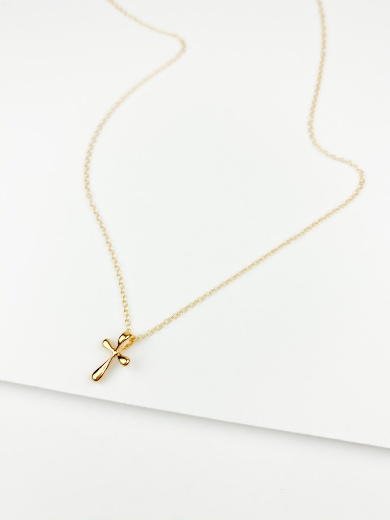 May include: A gold chain necklace with a small, delicate gold cross pendant.