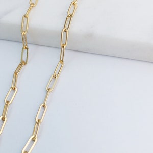 May include: A gold chain necklace with a delicate, linked design. The chain is made of small, oval-shaped links.