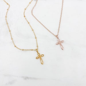 Puede incluir: Dos collares de oro con delicados colgantes de cruz. Uno es una cadena de oro rosa con un colgante de cruz m&aacute;s peque&ntilde;o, mientras que el otro es una cadena de oro con un colgante de cruz m&aacute;s grande.