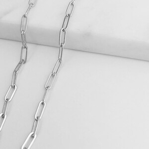 May include: A silver chain necklace with a simple, linked design. The chain is made of small, rectangular links.