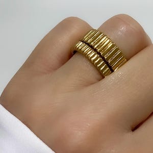 May include: Two gold-toned rings with a ridged design. The rings are stacked on top of each other.