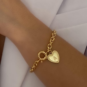 May include: A gold chain bracelet with a heart-shaped charm. The charm has a raised letter "A" on it.