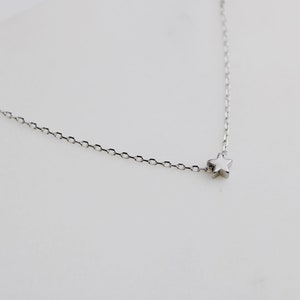 Peut inclure: Un collier fin en argent avec un petit pendentif en forme d'&eacute;toile.