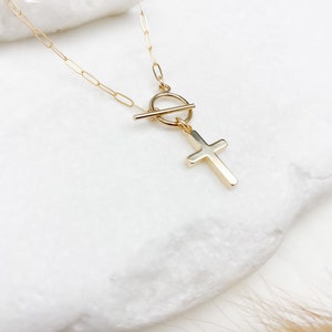 May include: A gold chain necklace with a toggle clasp and a cross pendant.