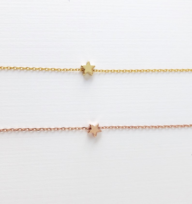Peut inclure: Deux cha&icirc;nes d&eacute;licates en or avec un petit pendentif en forme d'&eacute;toile. La cha&icirc;ne du haut est en or et la cha&icirc;ne du bas est en or rose.