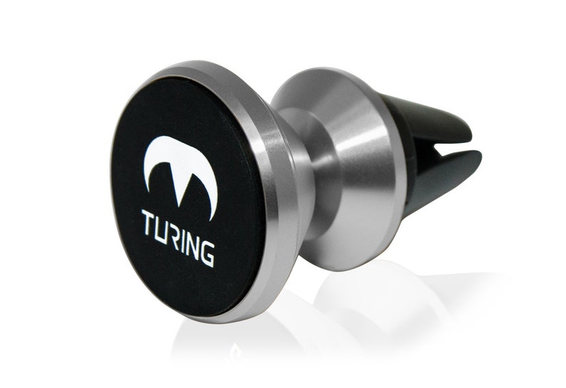 Pu&ograve; includere: Un supporto per telefono magnetico per auto in argento con una base magnetica nera. La base presenta il logo Turing e la scritta "TURING" stampata su di essa.