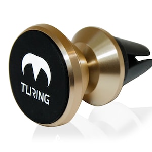 Pu&ograve; includere: Un supporto magnetico per telefono cellulare da auto color oro con una base circolare nera. La base ha un logo bianco con la parola "TURING" stampata su di essa.