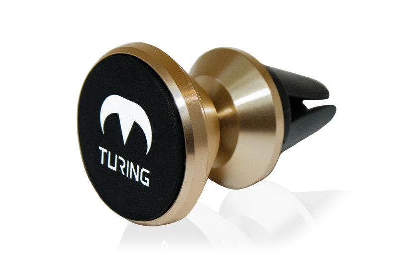Pu&ograve; includere: Un supporto magnetico per telefono cellulare da auto color oro con una base circolare nera. La base ha un logo bianco con la parola "TURING" stampata su di essa.